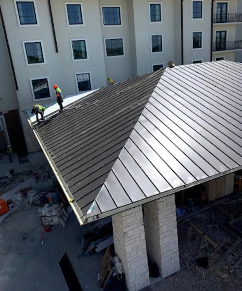 Crew installing standing seam metal roof panels on a commercial project in Shakopee
